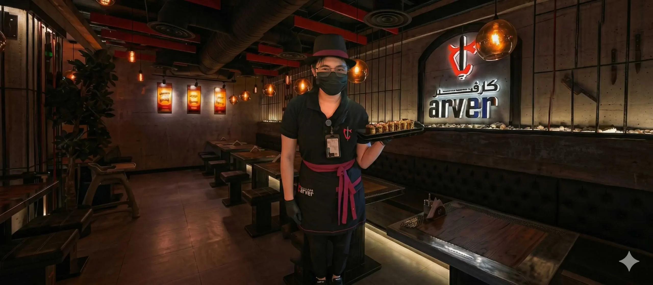 Waiter at Carver Steakhouse serving a main dish inside a luxury restaurant with warm lighting in Jeddah